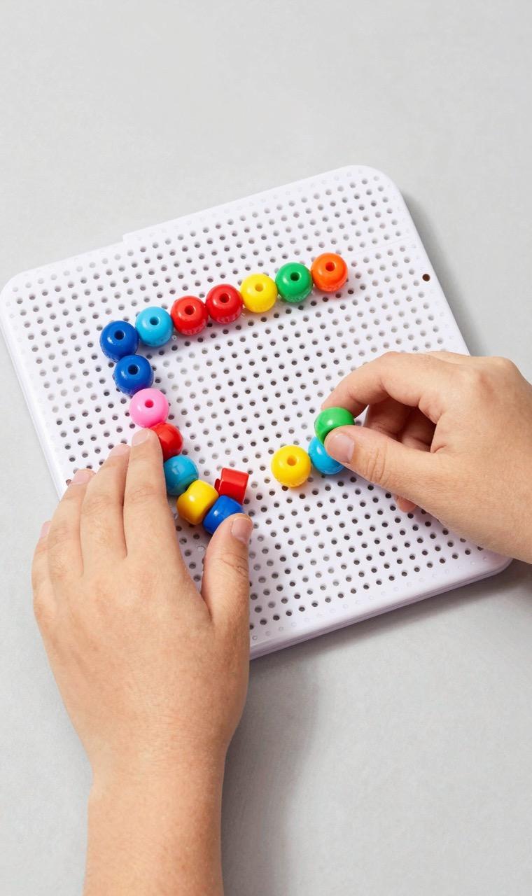 A child placing beads on a pegboard